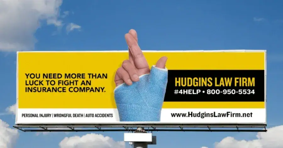 Billboard advertisement for Hudgins Law Firm featuring a hand with a bandaged finger and text emphasizing the need for legal support against insurance companies, including contact information and service details for personal injury and auto accidents.