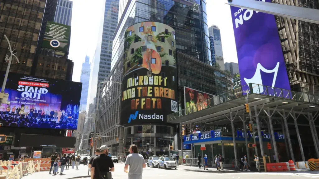 Times Square billboard showcasing Microsoft advertisement with vibrant graphics and Nasdaq logo, illustrating high-impact advertising in a bustling urban setting.