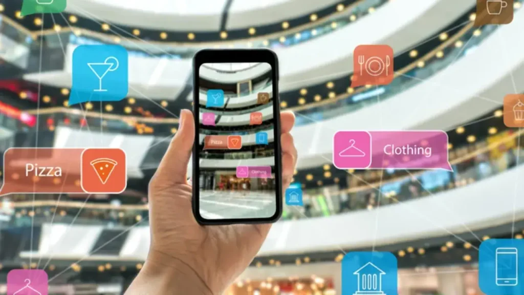 Hand holding smartphone displaying augmented reality icons for pizza, clothing, and dining options in a shopping mall.