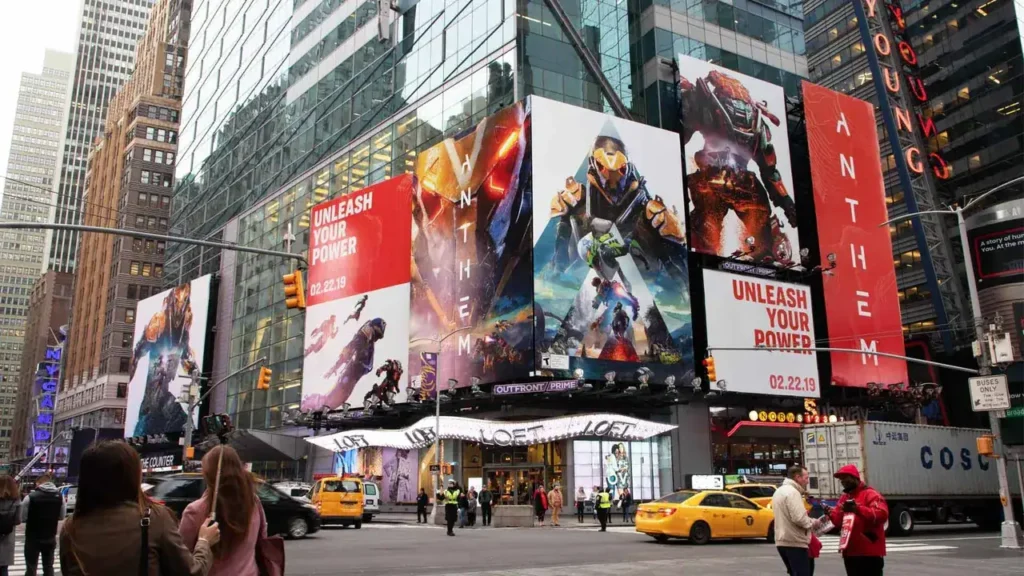 Billboards in Times Square showcasing vibrant advertisements for the video game "Anthem," featuring action-packed graphics and the tagline "Unleash Your Power," illustrating effective outdoor advertising strategies.