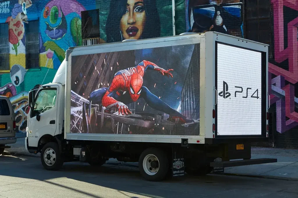 LED mobile billboard truck featuring Spider-Man artwork and PlayStation 4 branding, set against a vibrant urban mural backdrop.