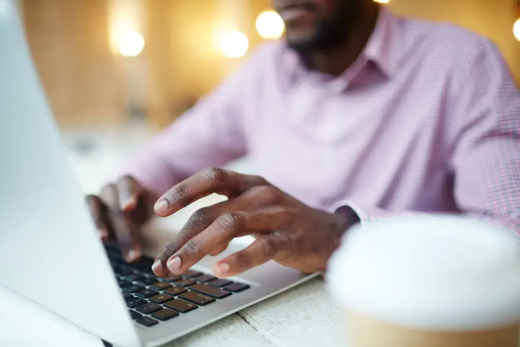 Person typing on laptop with coffee cup, representing digital marketing strategies and productivity in guerrilla marketing.