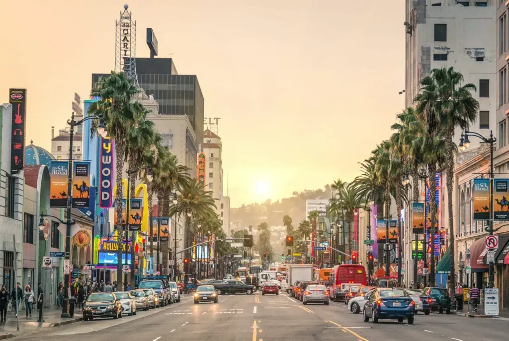 Hollywood Boulevard at sunset, featuring palm trees and vibrant advertising billboards, illustrating an urban marketing landscape.