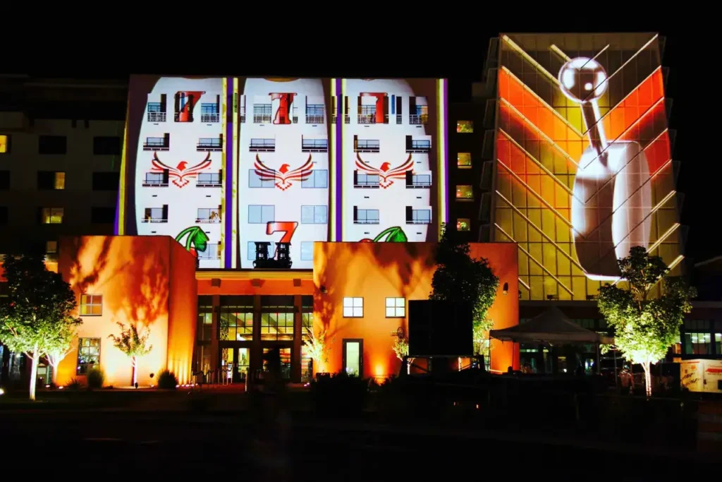 Building illuminated at night with vibrant projections showcasing creative advertisements, highlighting innovative guerrilla marketing techniques.