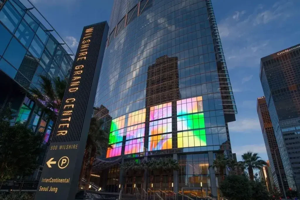High-rise building with colorful digital display on glass facade, showcasing modern advertising potential in urban settings.