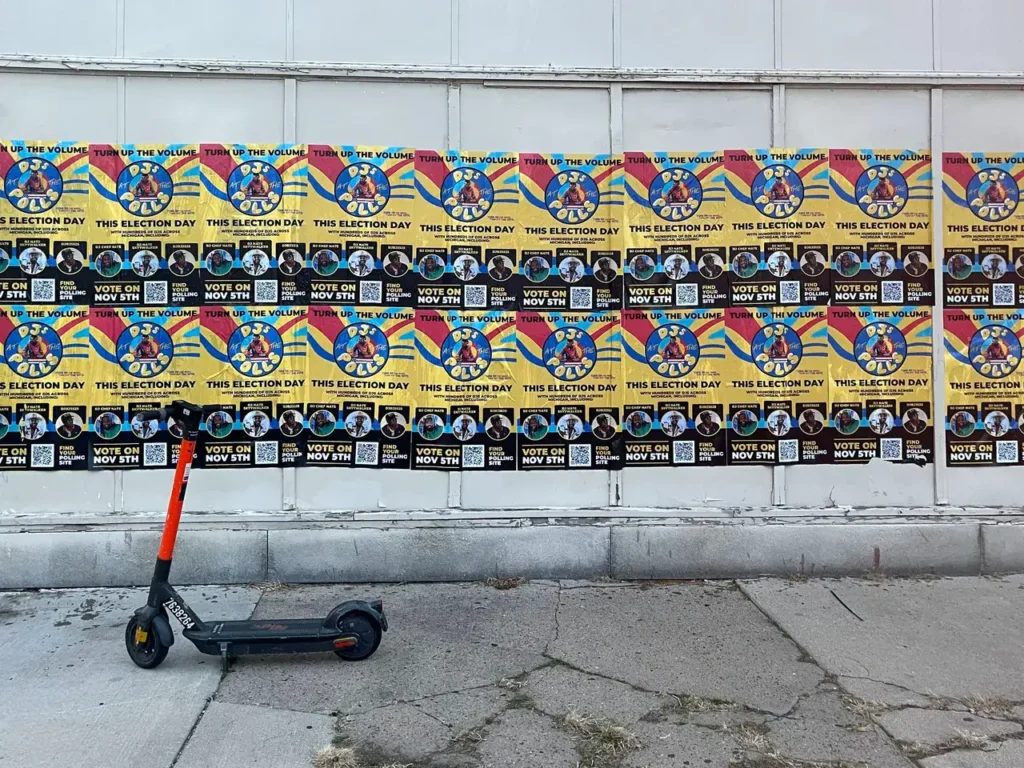 Scooter parked by election posters.