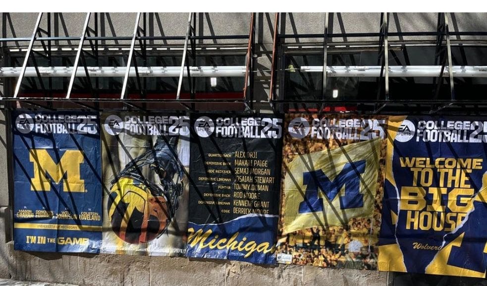 Banners promoting college football teams, featuring Michigan and Iowa logos, showcasing player names and the phrase "Welcome to the Big House," relevant to marketing strategies for sports events.