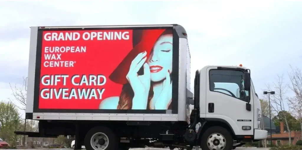 LED billboard truck advertising European Wax Center grand opening with promotional gift card giveaway.