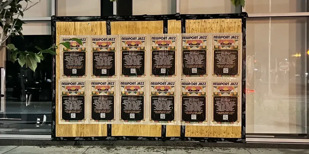 Newport Jazz Festival promotional posters displayed on a wooden board in an urban setting, highlighting guerrilla marketing strategies for event advertising.