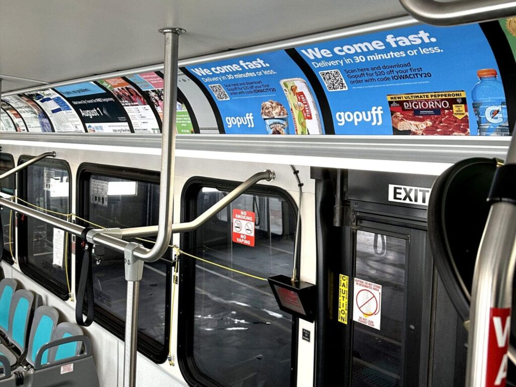 Interior of a bus featuring advertisements for goPuff, highlighting fast delivery services, with slogans and product images displayed on overhead panels.