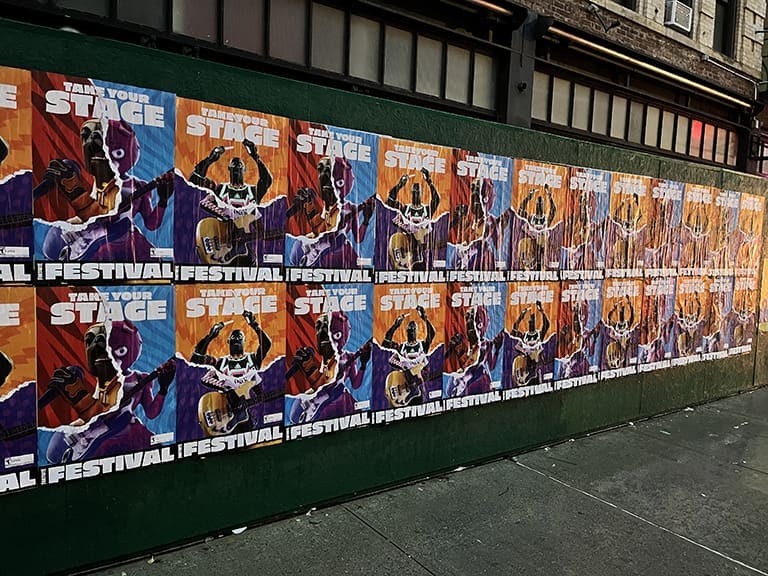 Colorful wall covered with promotional posters for a music festival featuring vibrant graphics and the slogan "Take Your Stage."