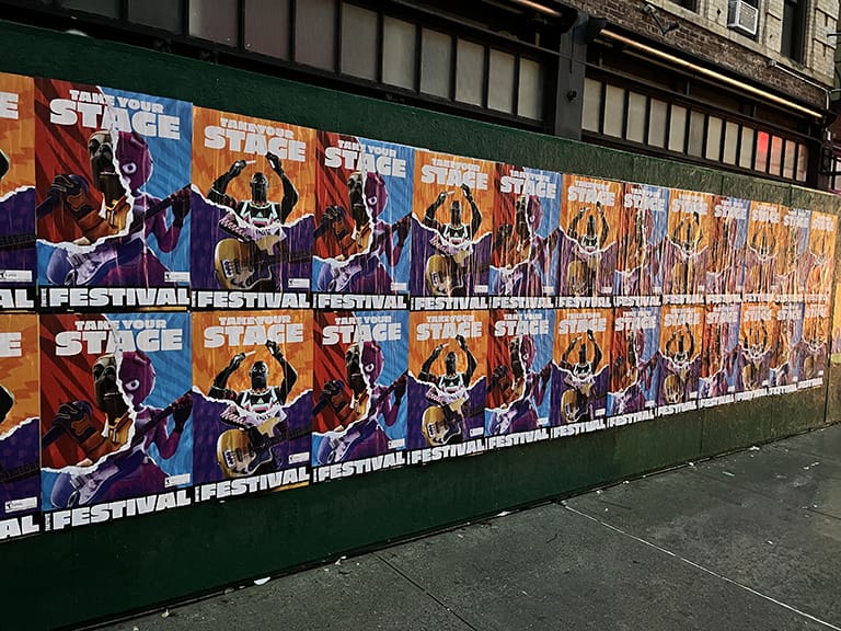 Colorful posters promoting a festival with the phrase "Transform Your Stage," featuring vibrant graphics and artistic designs, displayed in a dense arrangement on a city wall, reflecting urban guerrilla marketing strategies in Philadelphia.