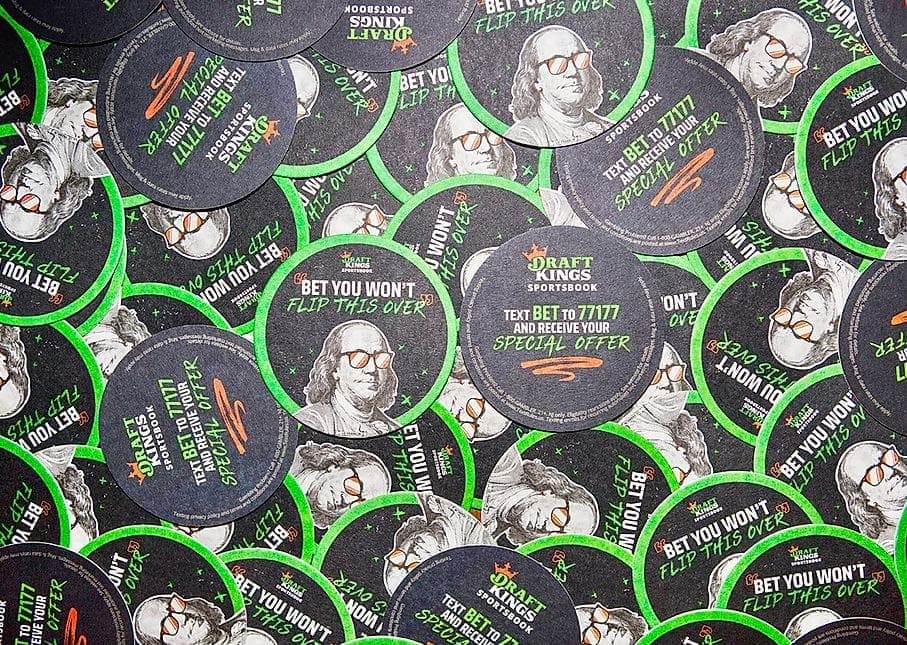 DraftKings Sportsbook promotional chips featuring the slogan "Bet You Won't Flip This Over" and instructions to text for a special offer, set against a vibrant green background.