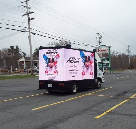 Truck displaying vibrant digital advertisement for Katy Perry, showcasing guerrilla marketing strategy in outdoor setting.
