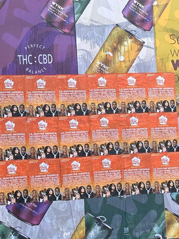 Promotional display featuring multiple flyers for Lil Wayne's event, showcasing vibrant graphics and branding related to guerrilla marketing strategies at conventions and tradeshows.