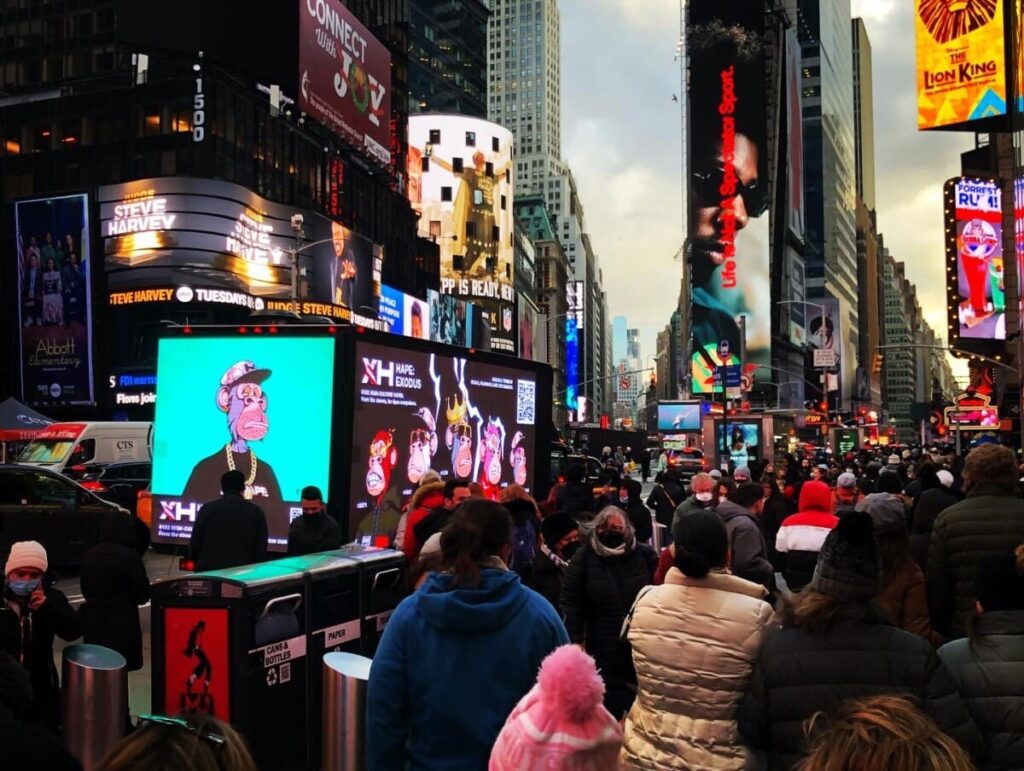 Crowd in Times Square with vibrant digital billboards, featuring animated characters and advertisements, highlighting guerrilla marketing tactics and urban advertising strategies.