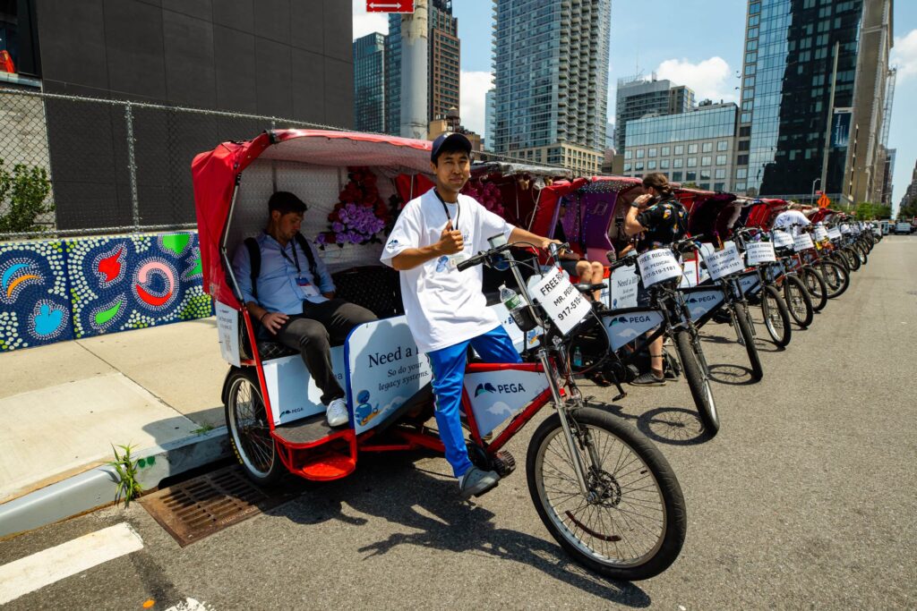 Pedicab drivers lined up on city street.