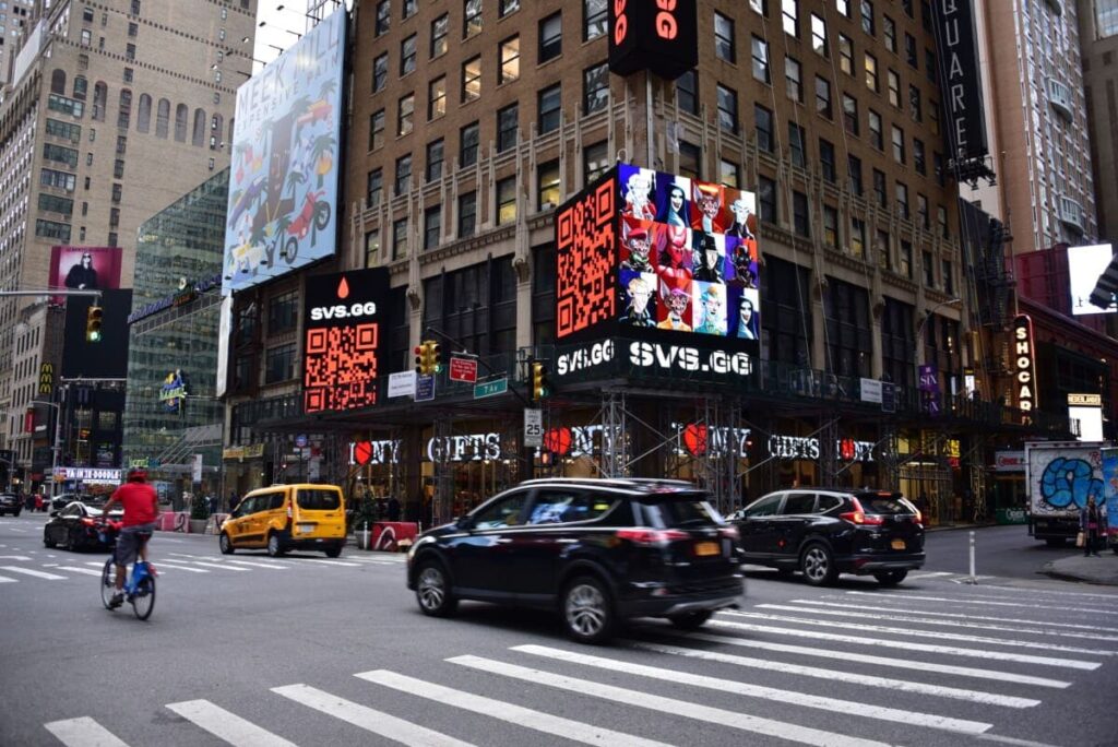 Busy urban intersection featuring digital billboards displaying QR codes and vibrant graphics, highlighting advertising strategies relevant to guerrilla marketing and outdoor advertising.
