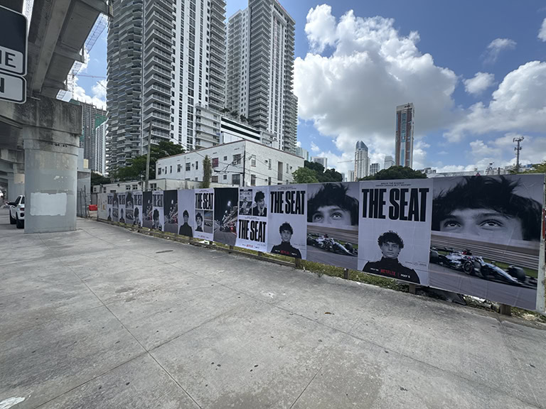 Posters on city sidewalk under blue sky.