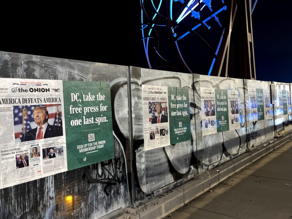 Satirical posters on a graffiti-covered wall.
