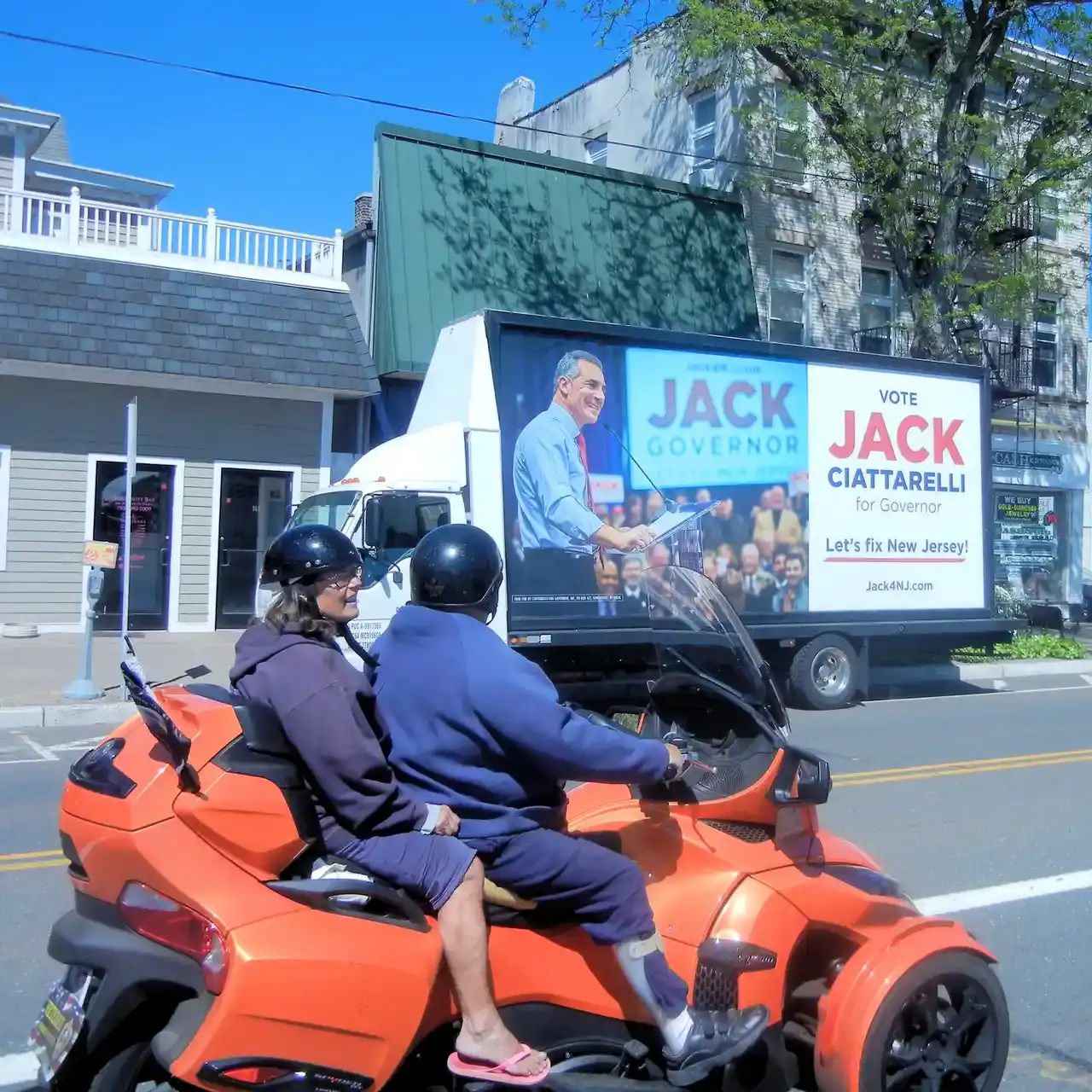 Mobile billboard truck displaying political campaign advertisement for Jack Ciattarelli, featuring "Vote Jack Governor" and "Let's fix New Jersey!" with two riders on an orange motorcycle in the foreground.
