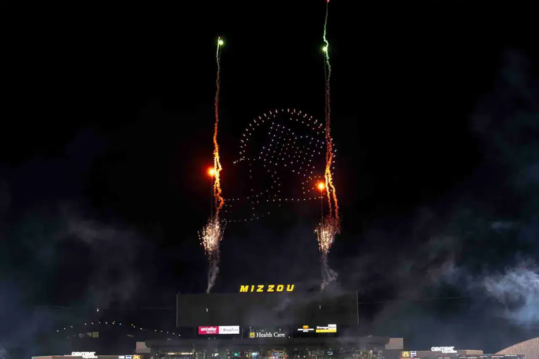 Drone light show featuring synchronized aerial displays and fireworks above Mizzou stadium, showcasing vibrant colors and patterns against a night sky.