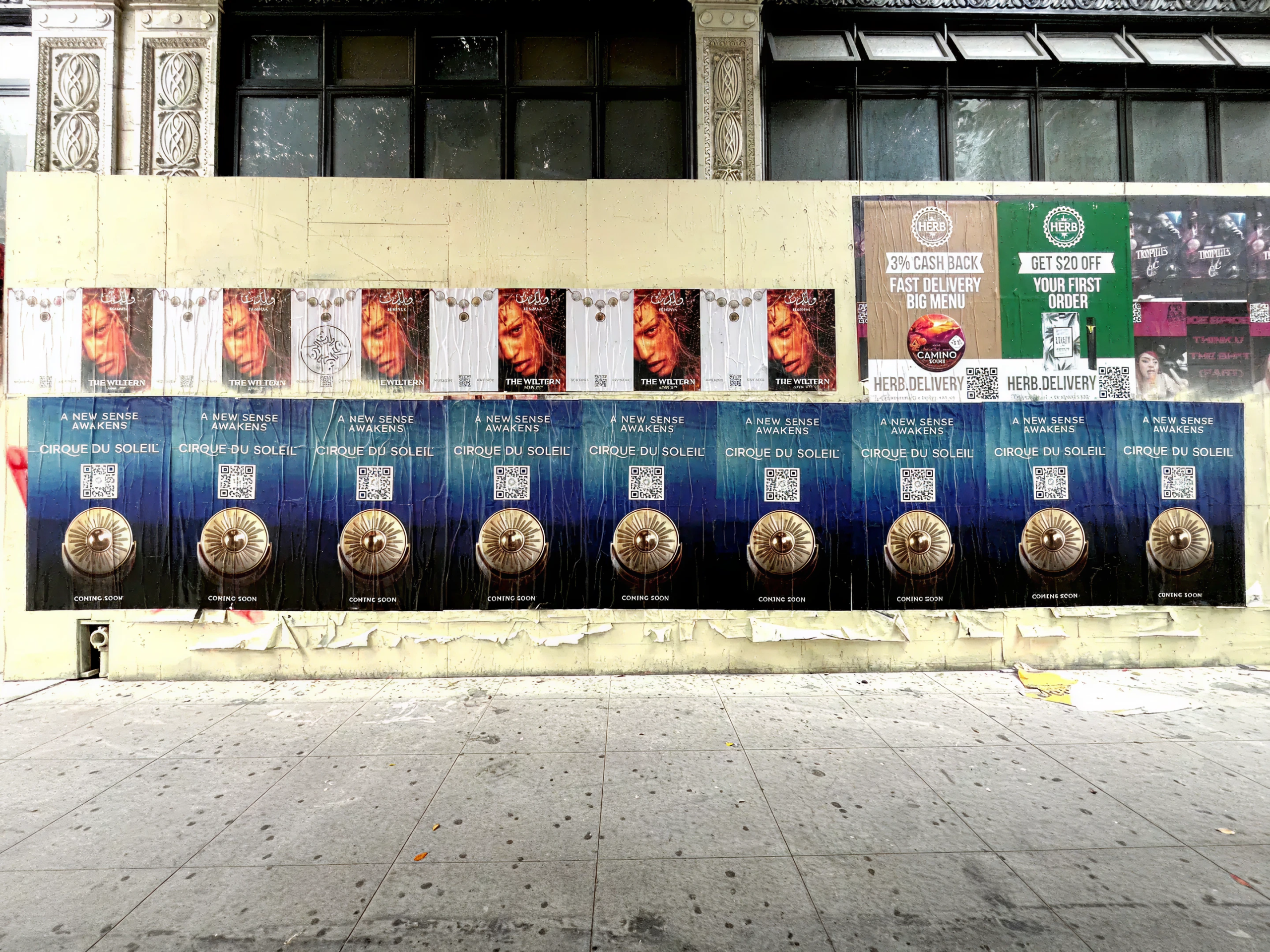 Wheatpaste wall featuring multiple Cirque du Soleil posters and advertisements, showcasing vibrant graphics and QR codes for interactive engagement, highlighting guerrilla marketing techniques in urban settings.