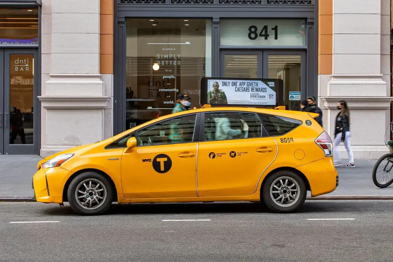 Yellow NYC taxi cab parked on city street, showcasing taxi advertising potential for brand visibility and marketing strategies.