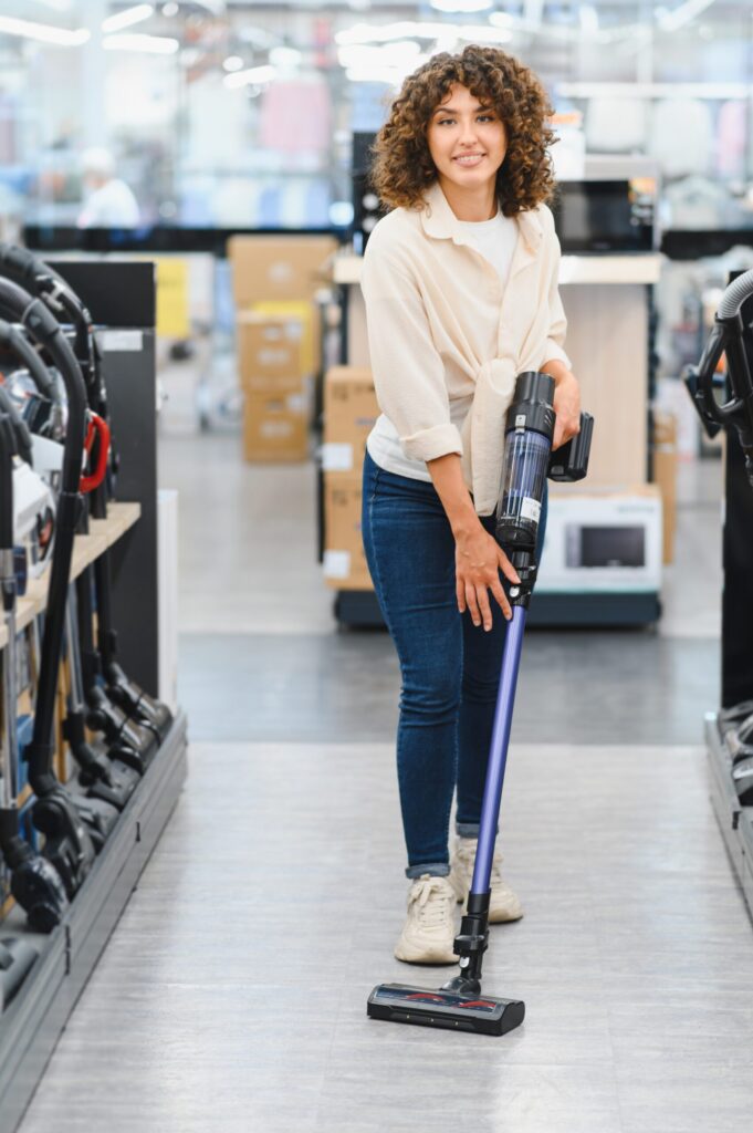 Person demonstrating a vacuum cleaner in store.