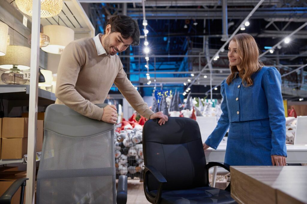 Couple shopping for office chairs in store.