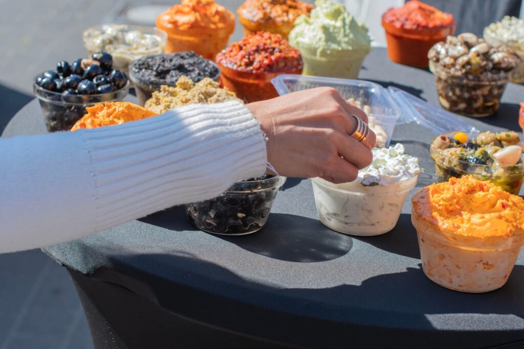 Hand reaching for assorted dips and toppings.