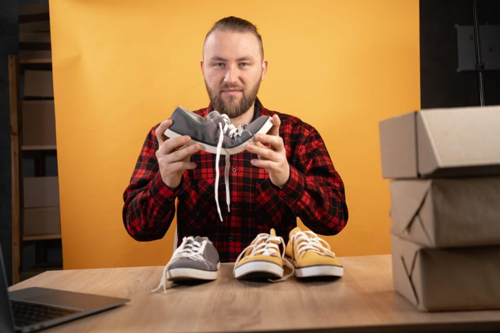 Man holding sneakers with shoe boxes nearby.