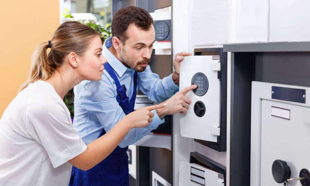 Two people examining a digital safe lock.