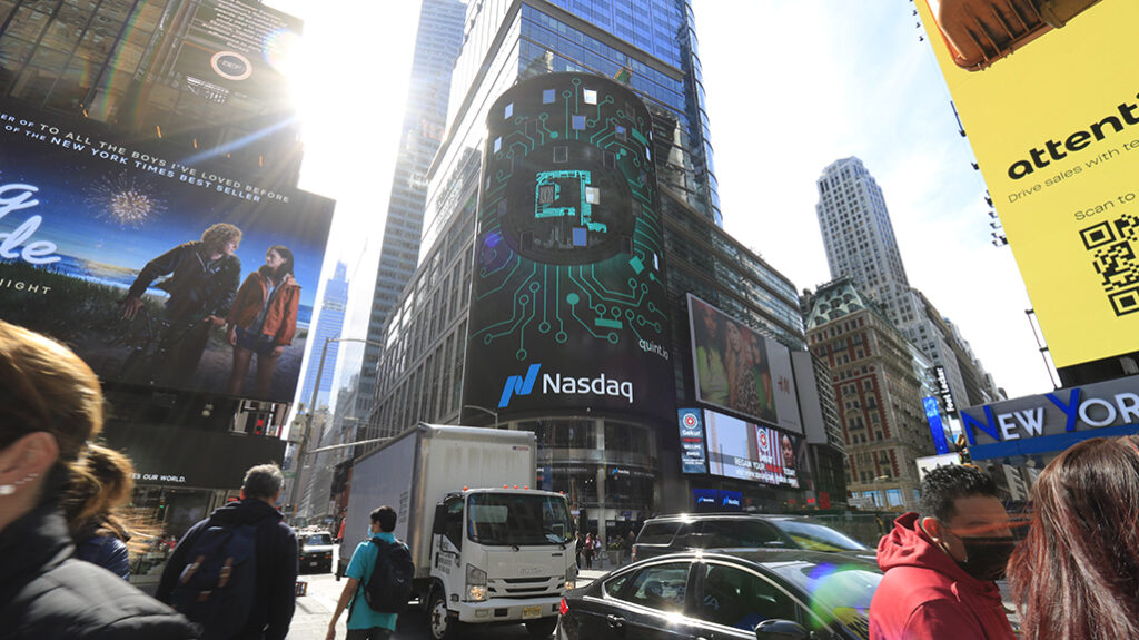 NASDAQ digital billboard in Times Square, Manhattan, showcasing vibrant graphics and branding amidst busy street activity.