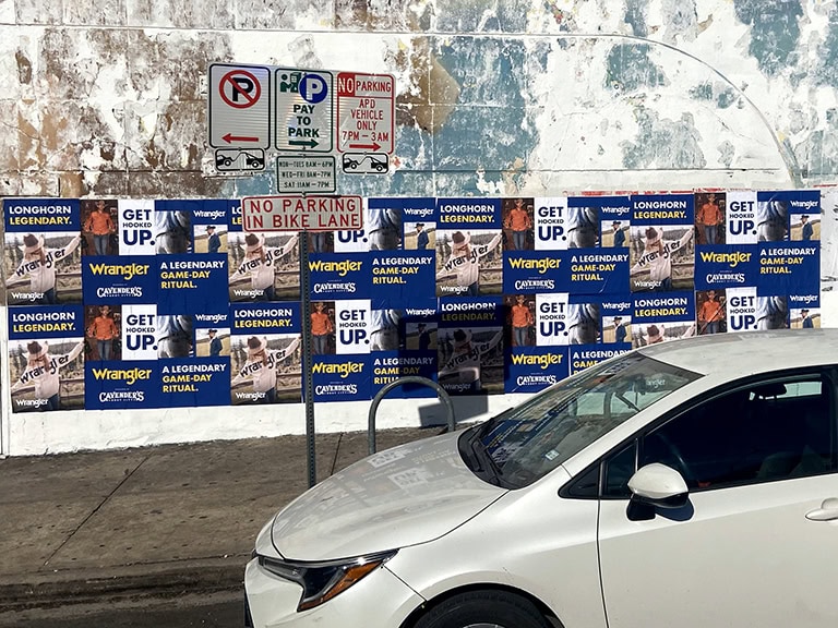 White car parked near advertising posters.