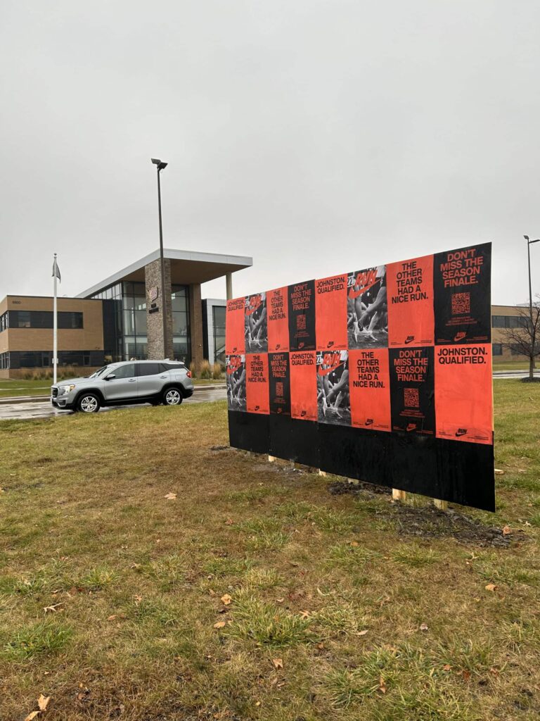 Posters on board near modern building exterior.