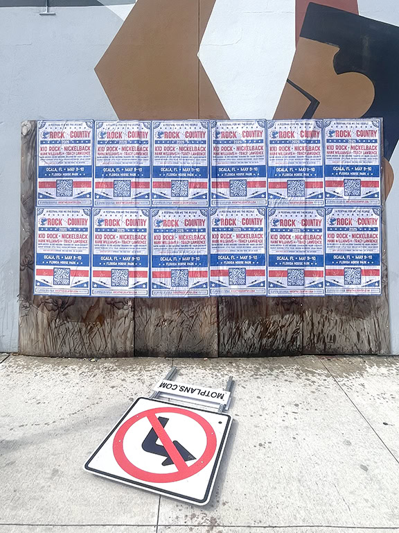 Posters on wall with fallen no-turn sign.