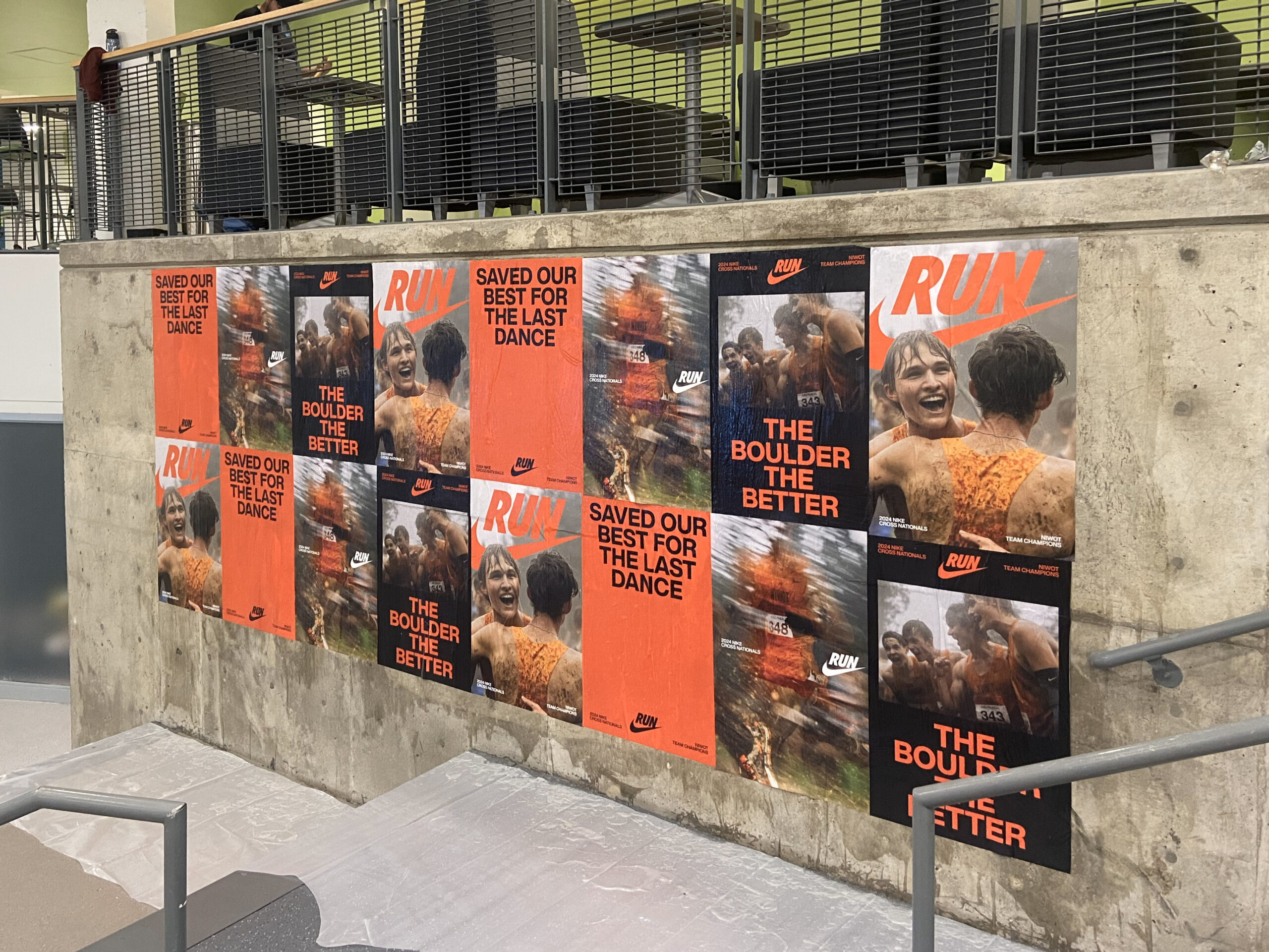 Posters featuring Nike advertisements with slogans "RUN," "SAVED OUR BEST FOR THE LAST DANCE," and "THE BOULDER THE BETTER," showcasing vibrant visuals of athletes, displayed on a concrete wall in an urban setting, illustrating guerrilla marketing techniques.