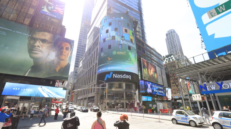 Times Square featuring the NASDAQ billboard displaying Microsoft advertisements, surrounded by bustling crowds and iconic skyscrapers, capturing the vibrant atmosphere of high-traffic urban advertising.