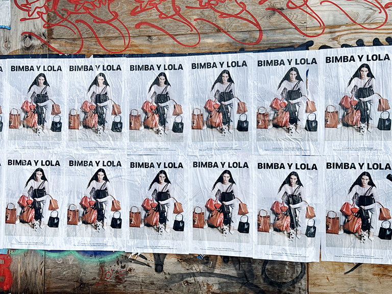 Wild wheat paste posting advertising featuring multiple posters for "Bimba y Lola" displayed on a textured wooden surface, showcasing guerrilla marketing techniques in New Hampshire.