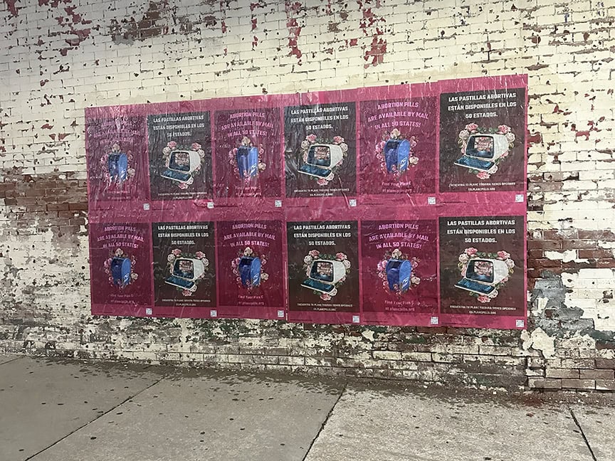 Colorful posters on a weathered brick wall.