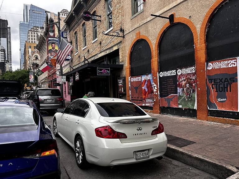 Street with parked cars and sports posters.