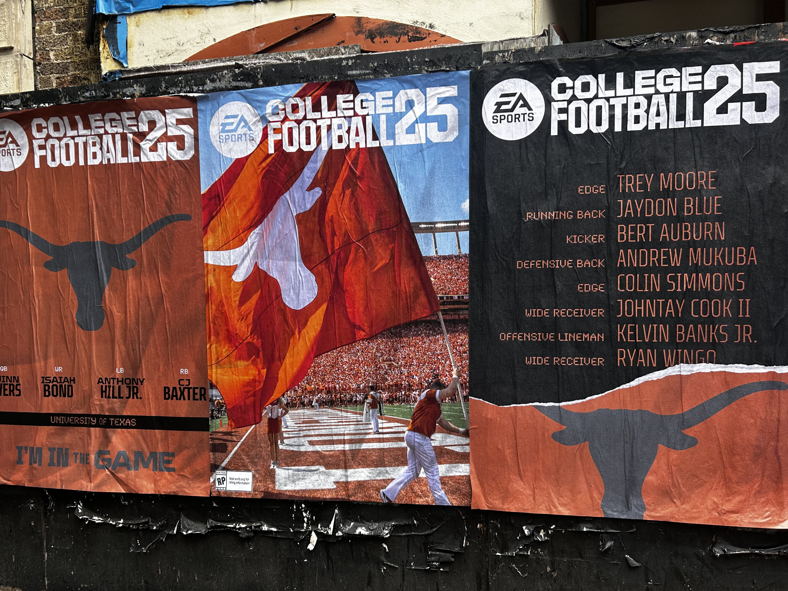 Wild wheat paste posting advertisement featuring EA Sports College Football 25 promotional banners, showcasing University of Texas branding and player names, integrating street art with guerrilla marketing strategies in Texas urban settings.