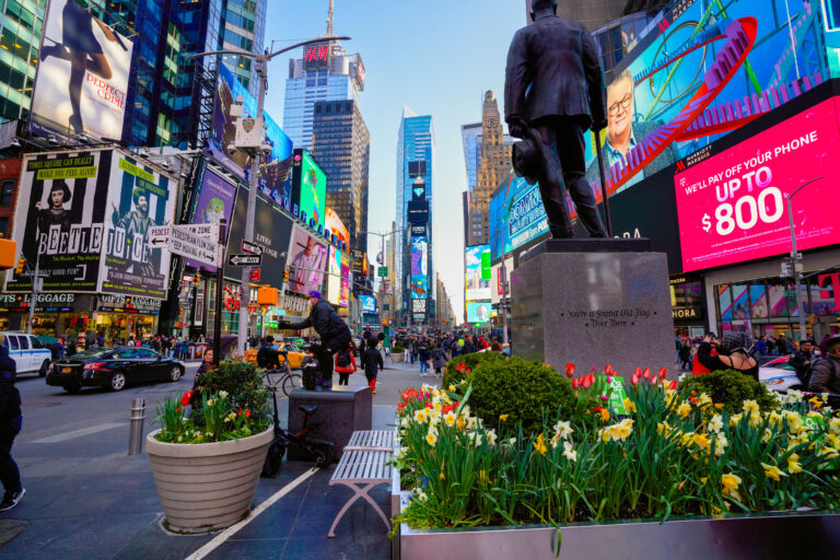 Times Square bustling with pedestrians, featuring vibrant billboards and a statue, showcasing the dynamic environment for the Diamond Peeps campaign by American Guerrilla Marketing.