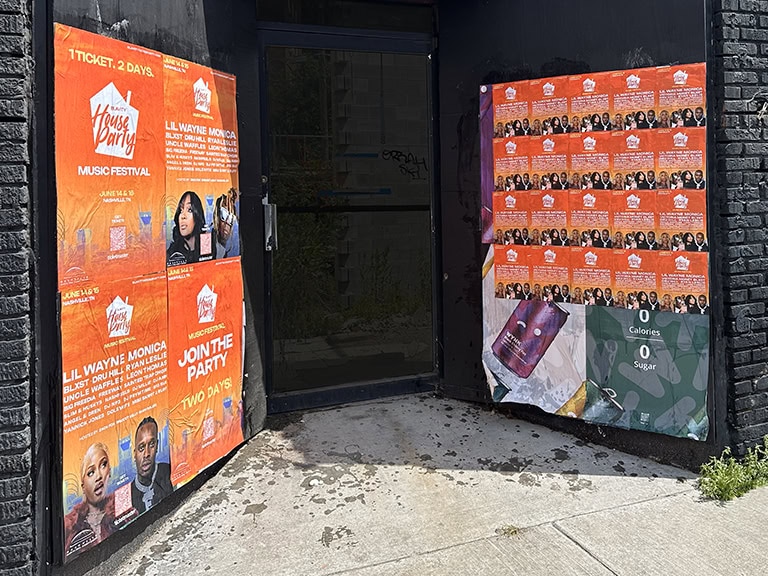 Orange music festival posters on black wall.
