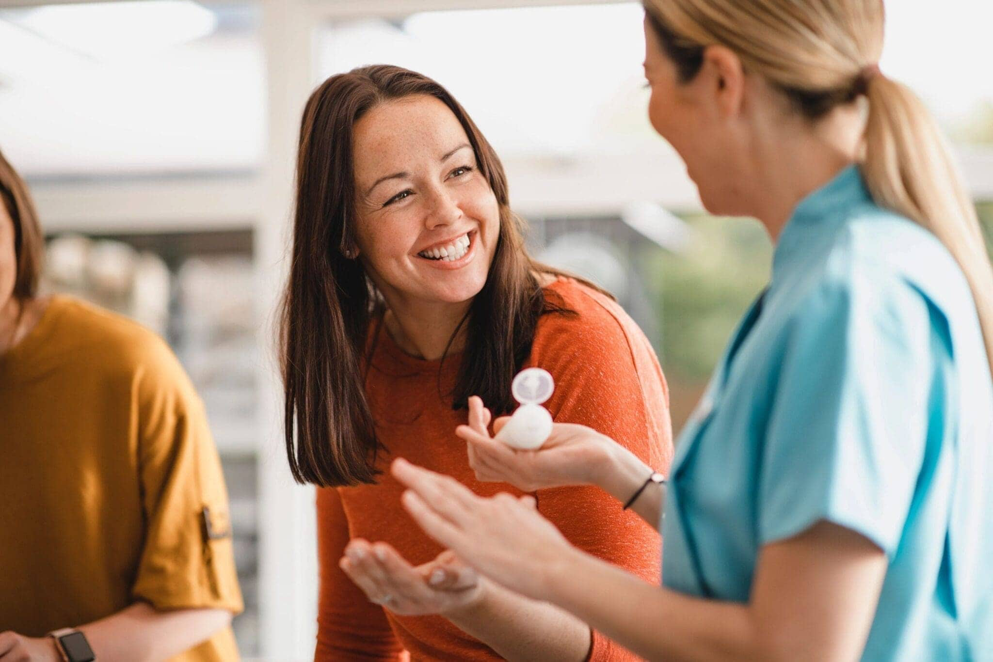 Smiling woman engaging with event staff during a product demonstration, showcasing interactive customer engagement.
