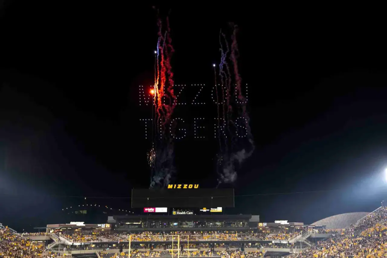 Fireworks spelling "MIZZOU TIGERS" above a stadium during a night event, showcasing a vibrant display in support of the Mizzou Tigers.