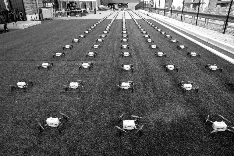 Rows of drones arranged on a grassy surface, showcasing American Guerrilla Marketing's drone light show setup for events.