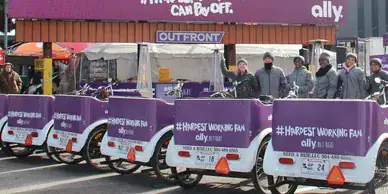 Bicycles with promotional branding for Ally, featuring "#HARDEST WORKING FAN" slogan, positioned in an outdoor event setting with staff members in winter attire.