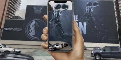 Hand holding smartphone displaying Augmented Reality basketball mural, showcasing innovative advertising potential for American Guerrilla Marketing.